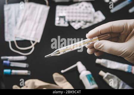 Diagnose und Behandlungskonzept für Coronaviren. Medicine Tabletten, Schutzmaske und Thermometer auf schwarzem Hintergrund. Medizin Konzept der Atemwege Stockfoto