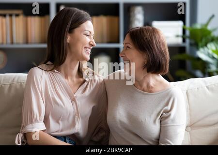 Glücklich reife Mutter und Tochter im Gespräch, sitzen auf der Couch zusammen Stockfoto