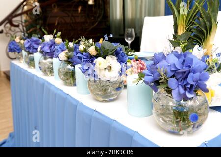 Dekoration von Hochzeitstisch mit Kerzen und Blumen in Blautönen, selektiver Fokus Stockfoto