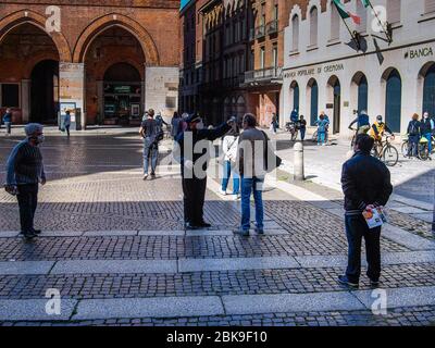 Cremona, Lombardei, Italien - 2. Mai 2020 - Menschen Schlange, um Zugang zu offenen Lebensmittelmarkt, Zugang von der Polizei kontrolliert Scannen nach Fieber-Test Stockfoto