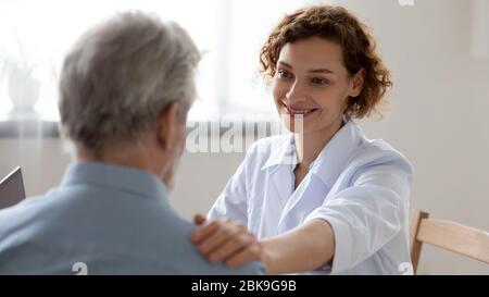 Lächelnde Ärztin beruhigt die Unterstützung von Patienten im Krankenhaus Stockfoto