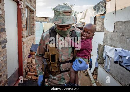 Peking, Südafrika. April 2020. Ein Soldat der südafrikanischen National Defense Force trägt ein Baby in seinem Arm in Johannesburg, Südafrika, 20. April 2020. Kredit: Yeshiel/Xinhua/Alamy Live News Stockfoto