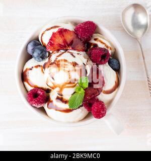 Kugeln aus Vanille-Eis in Becher mit Himbeere und Heidelbeeren Stockfoto