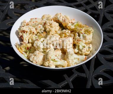 Eine Schüssel mit rohem Blumenkohl in runder Schüssel mit Chili bestreut Stockfoto