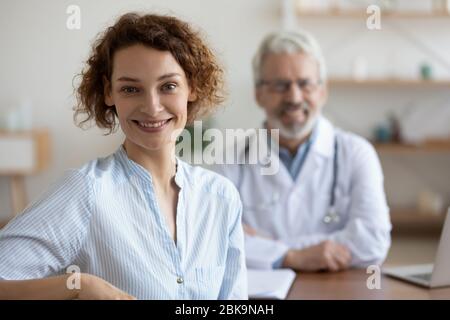 Glücklich gesunde junge Frau Patient Besuch alten männlichen Arzt, Porträt Stockfoto