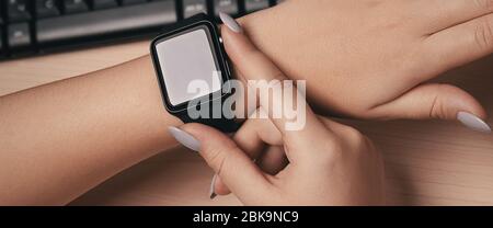 Frau, die die Smartwatch-Hand auf dem Schreibtisch berührt