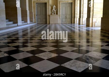 Paris / Frankreich - 6. Juli 2019: Großer schöner beigefarbener, leerer Flur mit schwarz-weißen Schachfliesen im Schloss Versailles. Barock Vintage st Stockfoto