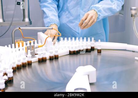 Ein Mann arbeitet in einer pharmazeutischen Fabrik. Visuelle Überwachung der Qualität der Interferonproduktion. Sterile Hormonproduktionslinie. Stockfoto