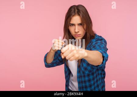 Porträt von selbstbewussten starken Mädchen in karierten Hemd mit geballten Fäusten in defensiver Haltung stehen, bereit, Täter zu schlagen, zeigt Boxen Geste. Stockfoto