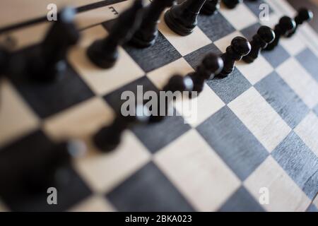 Ansicht des Schachbretts mit schwarzen Schachfiguren auf rustikaler Holzfläche Stockfoto