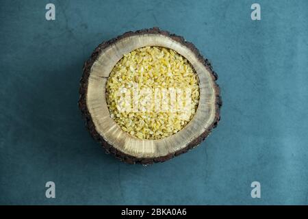 Rohbauchel in Holzschale auf Stein, Betonhintergrund. Gesunde, leckere und Bio-Getreide. Flach liegend, Draufsicht. Stockfoto