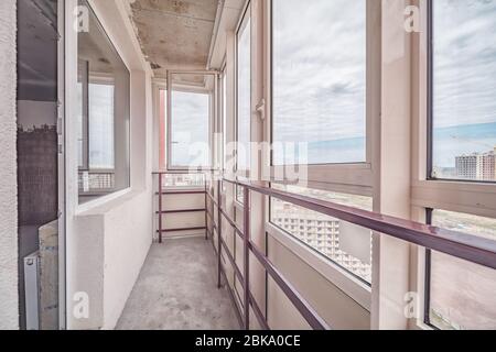 Kleiner Balkon im Inneren des modernen Apartmentgebäudes mit beigefliesten Böden und schwarzen Fensterrahmen Stockfoto