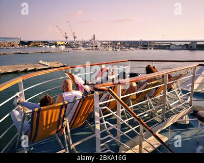 Passagiere einer Fähre auf Liegestühlen entspannen und in Urlaub fahren. Stockfoto