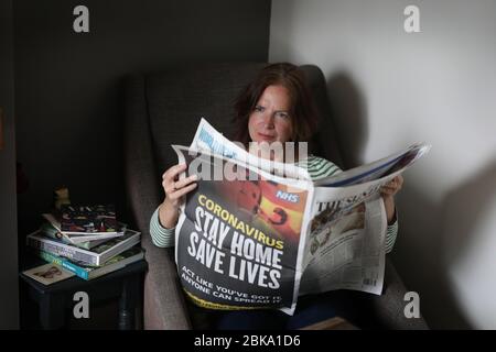 Eine Frau, die die Sunday Times Zeitung zu Hause während der Lockdown liest, weil die Coronavirus Pandemie die Welt fegt. Stockfoto