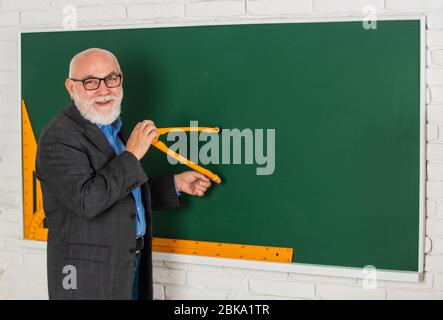 Bärtiger Tutor Mann zeichnen mit Kompass auf Tafel. Zurück zur Schule. Konzept der mathematischen grafischen Werkzeuge. In Richtung Wissen. Studieren Sie Mathematik, um gute Ergebnisse zu erhalten. Senior Mann Lehrer verwenden Kompass-Tool. Copy space. Stockfoto
