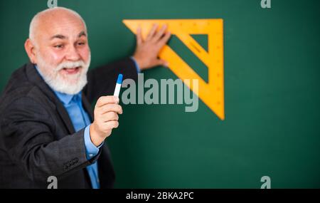 Logik, die beteiligt ist. Lieblingsthema. Senior Mann Lehrer verwenden mathematische Dreieck-Tool. Bärtige Tutor Mann an der Tafel. Zurück zur Schule. Mathematik und Menschen Konzept. Mathematik an Bord. Stockfoto