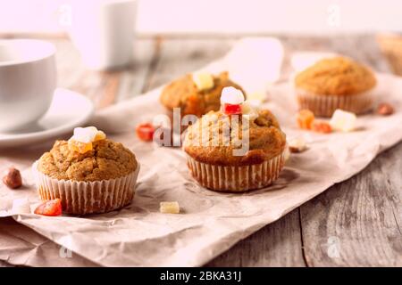 Frisch gebackene Banana Muffins mit kandierten Früchten lagen auf recyceltem Papier auf Holztisch. Frühstück am Morgen Stockfoto