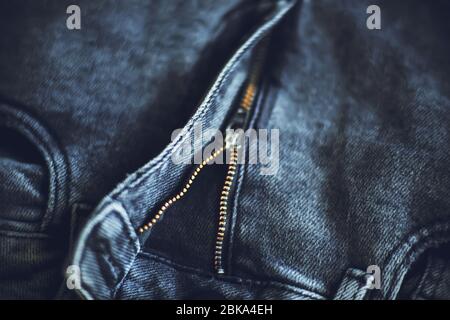 Das Oberteil aus dunkelgrauer modischer Jeans aus grobem Stoff, der mit einem Reißverschluss befestigt wird, beleuchtet von Licht. Stockfoto