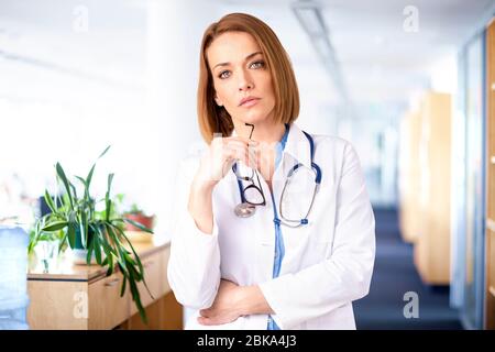 Porträtaufnahme einer Ärztin mittleren Alters, die im Krankenhausflur steht. Stockfoto