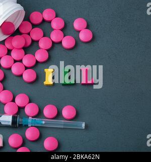 Eine Inschrift auf einem grauen Hintergrund, umgeben von leuchtend rosa Pillen und einer weißen Spritze aus einem weißen Glas verstreut. Das Konzept der Behandlung und PR Stockfoto