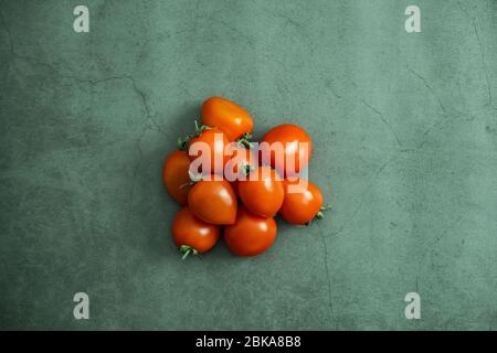 Rote kleine Kirschtomaten auf Stein, Betongrund. Frisch geerntetes leckeres, gesundes und biologisches Gemüse. Flach liegend, Draufsicht. Stockfoto