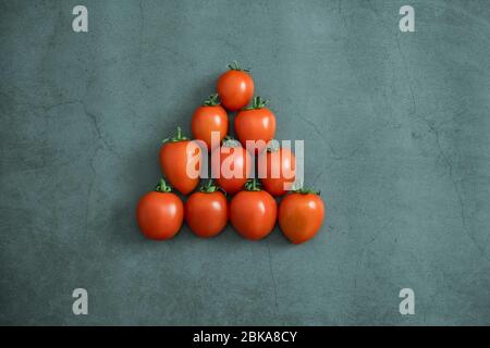 Rote kleine Kirschtomaten auf Stein, Betongrund. Frisch geerntetes leckeres, gesundes und biologisches Gemüse. Flach liegend, Draufsicht. Stockfoto