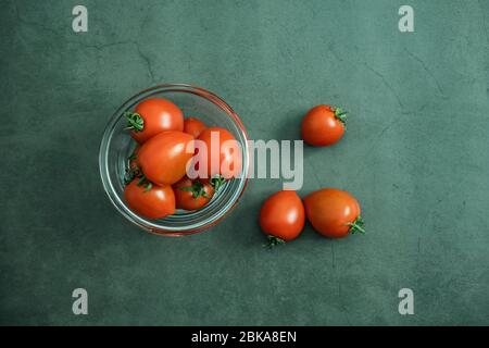 Kirschtomaten in Glasschüssel auf Stein, Betonhintergrund. Frisch geerntetes leckeres, gesundes und biologisches Gemüse. Flach liegend, Draufsicht. Stockfoto