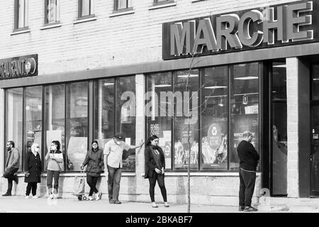 Menschen Schlange vor Supermarkt unter Wahrung der sozialen Distanz in der Einwanderer-Arbeitsviertel Park Extension in Montreal Kanada Stockfoto