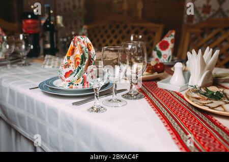 Dinner-Set auf einem Tisch mit Vintage-Creme Spitze Tischdecke und Servietten, elegante Porzellangeschirr, Besteck und Kristallglas angeordnet Stockfoto