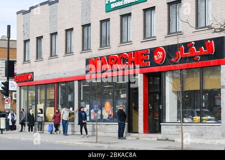 Menschen Schlange vor Supermarkt unter Wahrung der sozialen Distanz in der Einwanderer-Arbeitsviertel Park Extension in Montreal Kanada Stockfoto