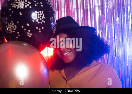 Junge schwarze Frau sieht glücklich aus, während Sie Zeit im Nachtclub verbringen. Geburtstagsfeier und Nachtleben Konzept. Stockfoto