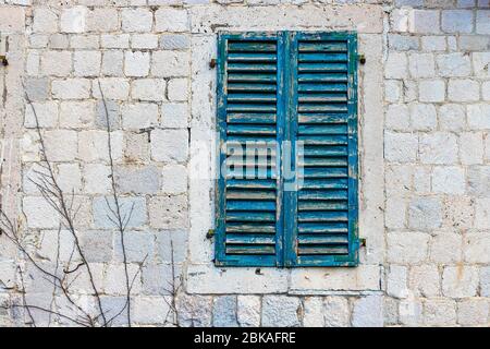 Authentisches Haus mit einer Steinmauer, mit schönen alten offenen Fenstern und mit grünen Fensterläden und mit Vasen am Fenster. Montenegro Stockfoto