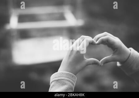 Herz aus Fingern, Hände eines kleinen Mädchens auf einem Spielplatz Stockfoto