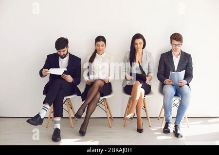 Geschäftsleute, die auf die Einstellung von Bewerbungsgesprächen warten, sitzen auf einem Stuhl im Büro. Stockfoto