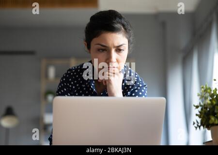 Kopfschuss konzentrierte junge indische Frau Blick auf Laptop-Monitor. Stockfoto