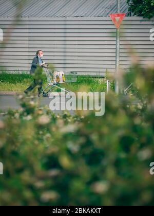 Bukarest/Rumänien - 05.01.2020: Mann mit einer Facemask, der einen mit Taschen gefüllten Warenkorb schiebt. Stockfoto