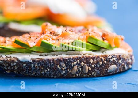 Sandwiches mit geräuchertem Lachs und Avocado auf blauem Hintergrund. Konzept für eine gesunde Ernährung. Stockfoto