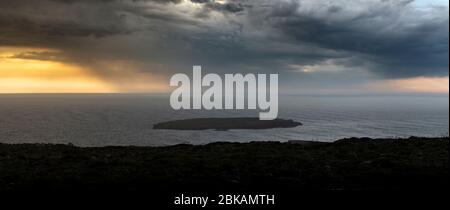 Ein stürmischer Sonnenuntergang über einer kleinen Insel am Cap de Cavalleria im Norden von Menorca, Spanien Stockfoto