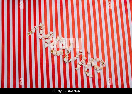 Popcornkörner in Film Wort auf rot weiß gestreiften Hintergrund angeordnet. Stockfoto