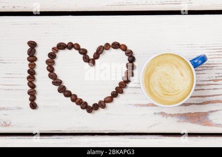 Flach legen blaue Tasse Kaffee und Bohnen in einem Herzen angeordnet. Stockfoto