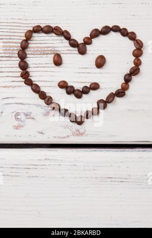Kaffeebohnen in Form von Smiley mit herzförmigem Kopf angeordnet. Stockfoto