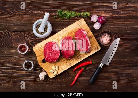 Draufsicht von mariniertem Rinderfilet Mignon mit Gewürzen auf Holztisch Stockfoto