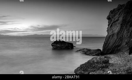 Lange Belichtung photograhy am felsigen Kato Petres Strand Landschaft in der Abenddämmerung. Rhodos, Griechenland Stockfoto