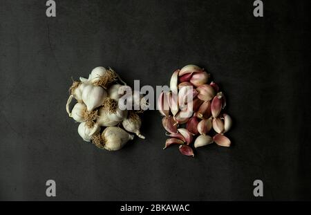 Knoblauchzwiebeln und Extrakte auf schwarzem Hintergrund. Blick von oben auf köstliche Garlics. Stockfoto