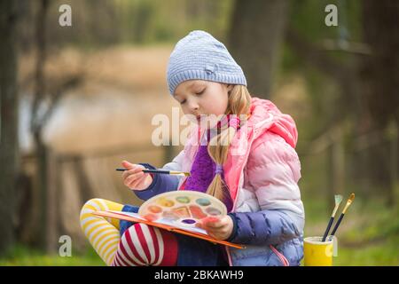 Das kleine Mädchen malt im Frühling auf die Natur Stockfoto