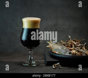 Dunkles Bierglas und gesalzene getrocknete Fischgerichte Stockfoto