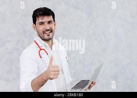 Glücklich Arzt gut aussehend männlichen Daumen nach oben gute Arbeit mit Computer-Laptop. Stockfoto