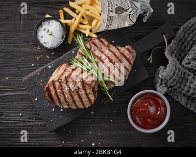 Gegrillte Rindersteaks auf einem dunklen Holztisch, Draufsicht Stockfoto