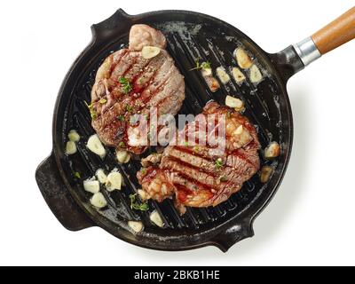 Pfanne von gegrillten Rindersteaks mit Knoblauch und Gewürzen auf weißem Hintergrund isoliert Stockfoto