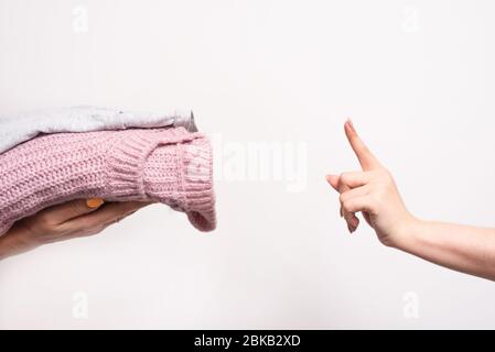 Hören Sie auf, all Ihre deklassierten Sachen zu spenden. Das Mädchen übergibt während der Coronavirus-Pandemie alte Kleidung als Spende und humanitäre Hilfe. Stockfoto